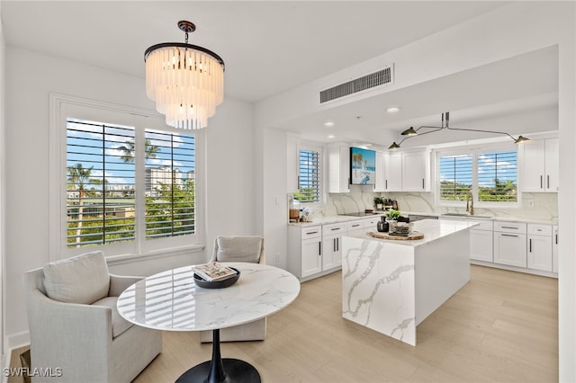 kitchen with white cabinetry, a kitchen island, and a notable chandelier