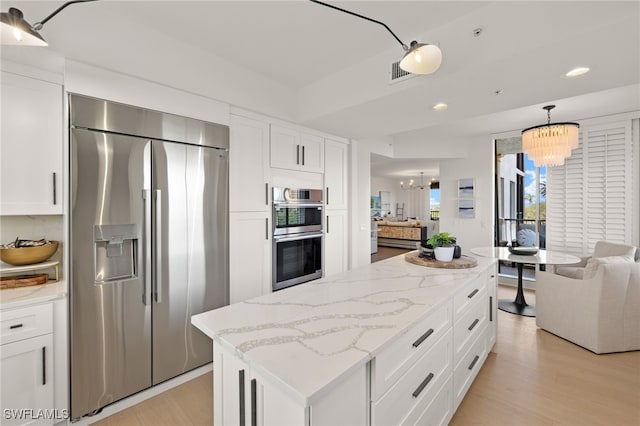 kitchen featuring a center island, white cabinets, decorative light fixtures, stainless steel appliances, and a chandelier