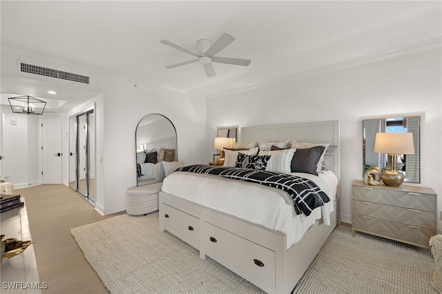 bedroom with light wood-type flooring, ceiling fan with notable chandelier, and ornamental molding