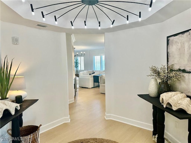 corridor featuring light hardwood / wood-style flooring and a notable chandelier