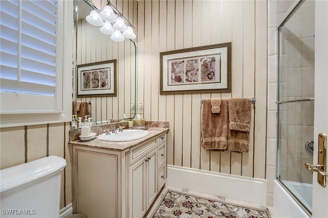 full bathroom featuring vanity, bath / shower combo with glass door, and toilet