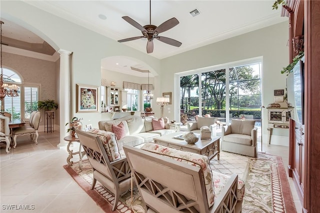 tiled living room featuring ornate columns, crown molding, and ceiling fan with notable chandelier