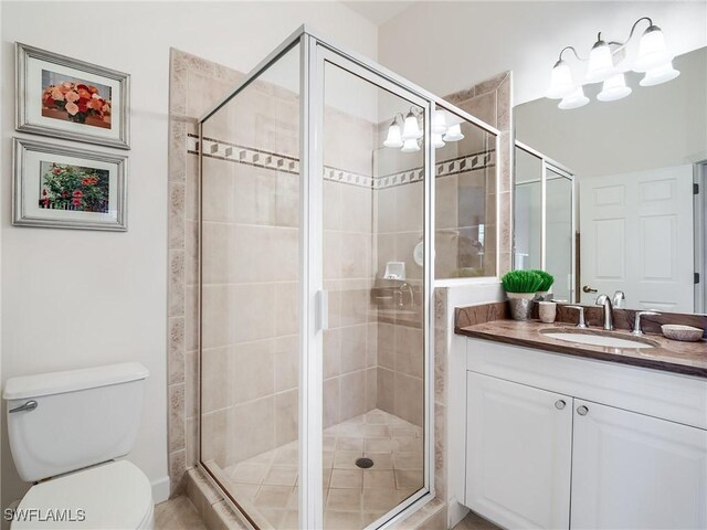 bathroom with toilet, a shower with door, and vanity