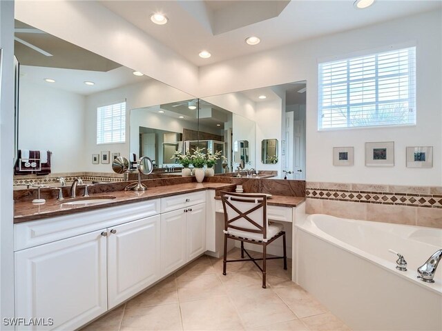 bathroom featuring a wealth of natural light, tile patterned flooring, a tub to relax in, and vanity