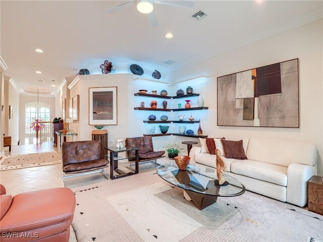 living room with light tile patterned floors, ceiling fan with notable chandelier, and ornamental molding