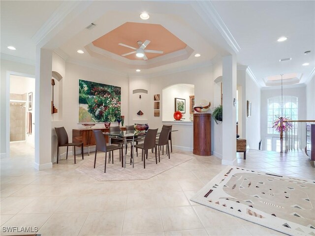 tiled dining area featuring ceiling fan with notable chandelier, ornamental molding, and a raised ceiling