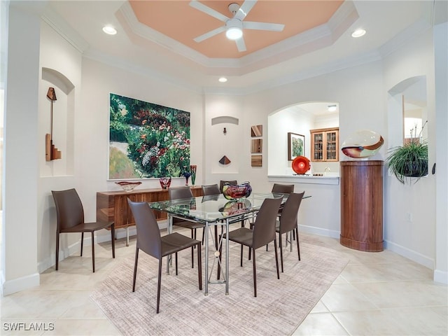 dining room with a raised ceiling, ornamental molding, light tile patterned flooring, and ceiling fan