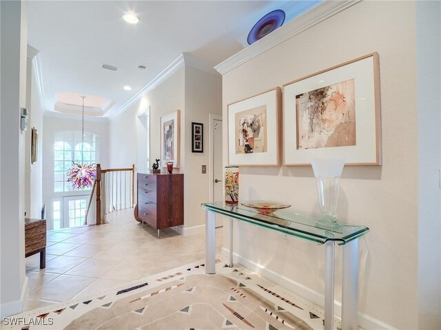 hallway featuring an inviting chandelier, ornamental molding, a raised ceiling, and light tile patterned floors