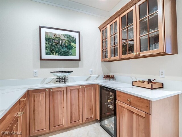 interior space featuring light tile patterned floors, light stone countertops, beverage cooler, and ornamental molding