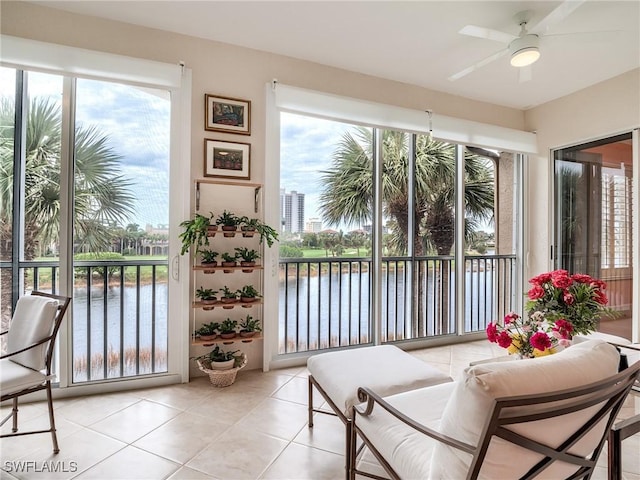 sunroom / solarium with ceiling fan and a water view