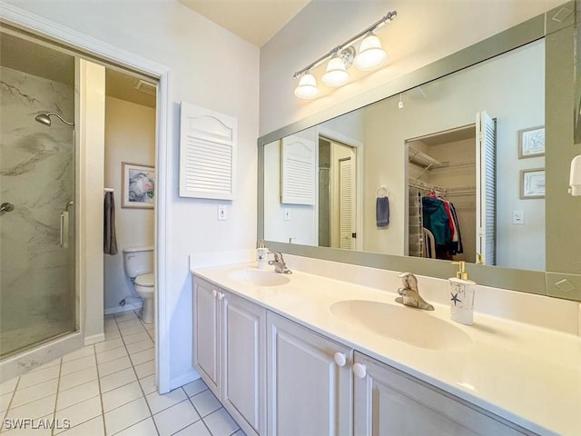 bathroom with tile patterned floors, vanity, a shower with shower door, and toilet