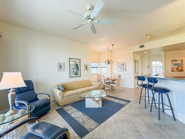 tiled living room featuring ceiling fan with notable chandelier