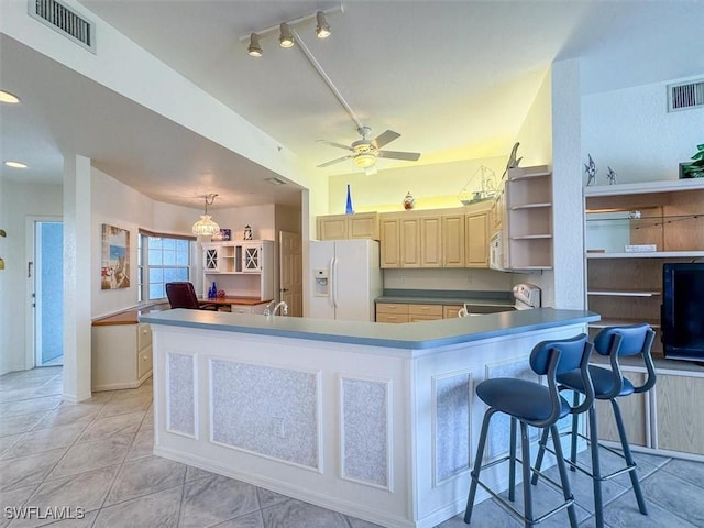 kitchen with ceiling fan, white refrigerator with ice dispenser, kitchen peninsula, stove, and a kitchen bar