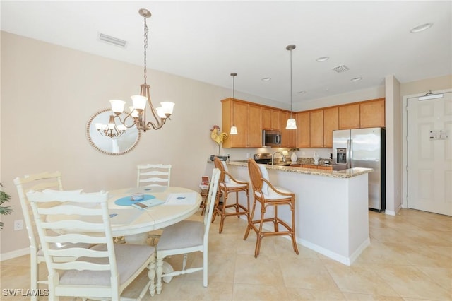 9067 Capistrano St N Unit 4502, Naples, FL 34113 - kitchen with kitchen peninsula, light stone countertops, stainless steel appliances, an inviting chandelier, and hanging light fixtures