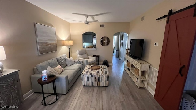 living room with hardwood / wood-style flooring, ceiling fan, and a barn door