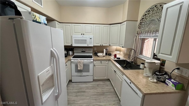 kitchen featuring white appliances, light hardwood / wood-style floors, white cabinetry, and sink