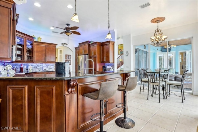 kitchen featuring decorative light fixtures, light tile patterned floors, ceiling fan with notable chandelier, decorative backsplash, and crown molding