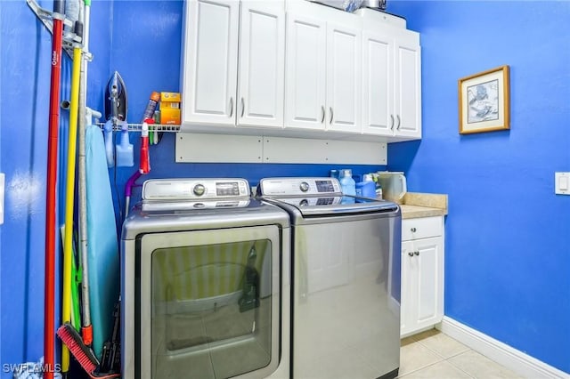 laundry area featuring separate washer and dryer, cabinets, and light tile patterned floors