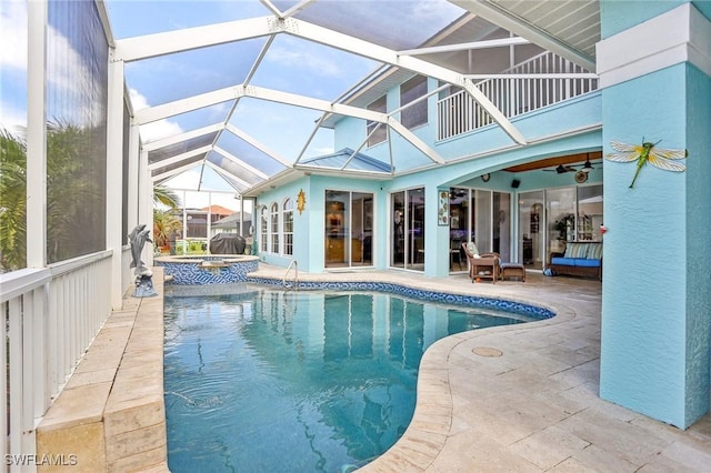 view of pool featuring a patio area, ceiling fan, an in ground hot tub, and glass enclosure