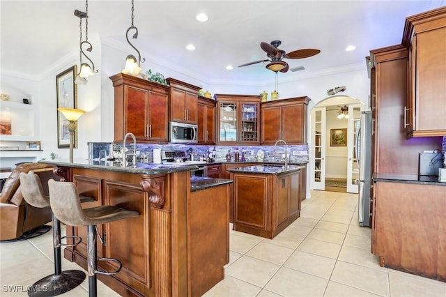 kitchen featuring stainless steel appliances, ceiling fan, kitchen peninsula, decorative backsplash, and pendant lighting