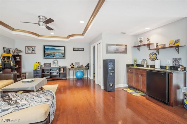 living room featuring sink, a raised ceiling, ceiling fan, wood-type flooring, and crown molding