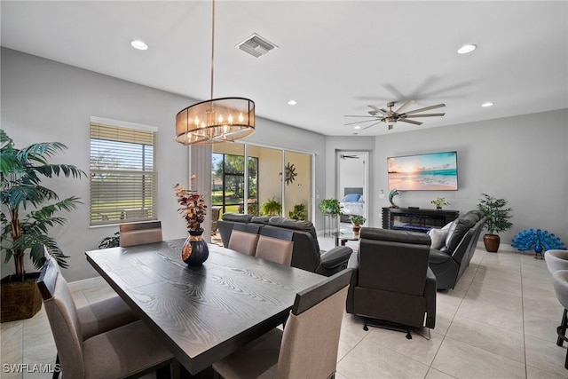 tiled dining room with ceiling fan with notable chandelier