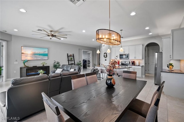 tiled dining room featuring ceiling fan with notable chandelier