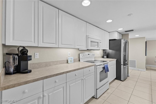 kitchen with white cabinetry, light tile patterned floors, and white appliances