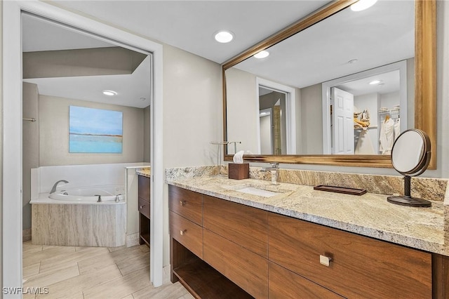 bathroom with vanity and tiled tub