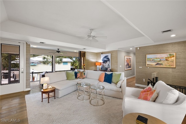 living room with hardwood / wood-style floors, ceiling fan, and a tray ceiling