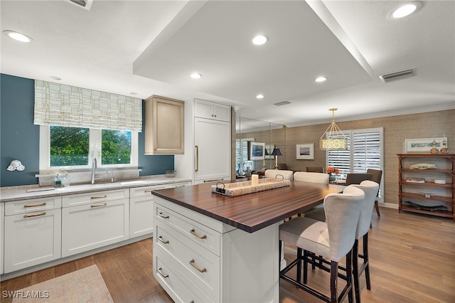 kitchen featuring butcher block countertops, a center island, white cabinets, and pendant lighting