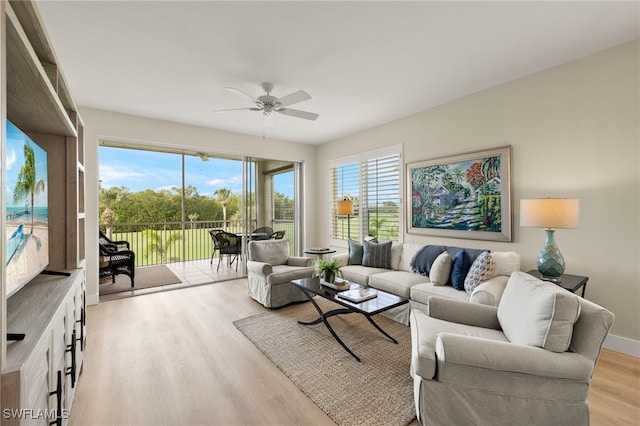 living room featuring baseboards, light wood-style flooring, and a ceiling fan