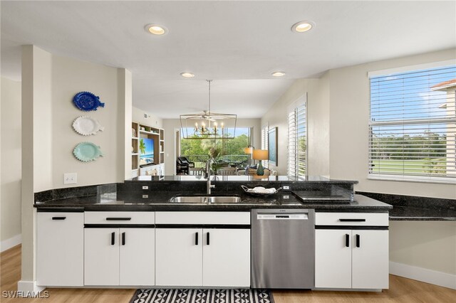 kitchen with stainless steel dishwasher, a sink, white cabinetry, and an inviting chandelier