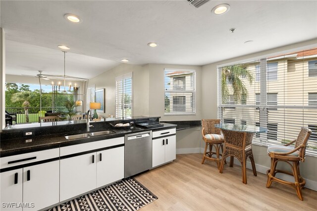 kitchen with white cabinets, light wood-type flooring, stainless steel dishwasher, pendant lighting, and a sink