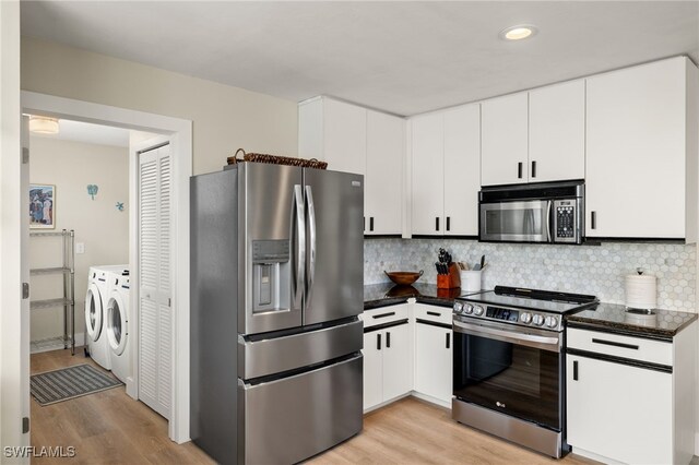 kitchen featuring washing machine and dryer, light wood-style flooring, appliances with stainless steel finishes, decorative backsplash, and dark countertops