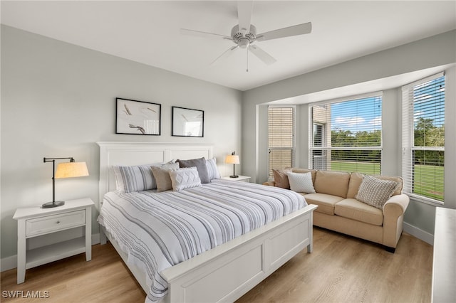 bedroom featuring a ceiling fan, light wood-style flooring, and baseboards