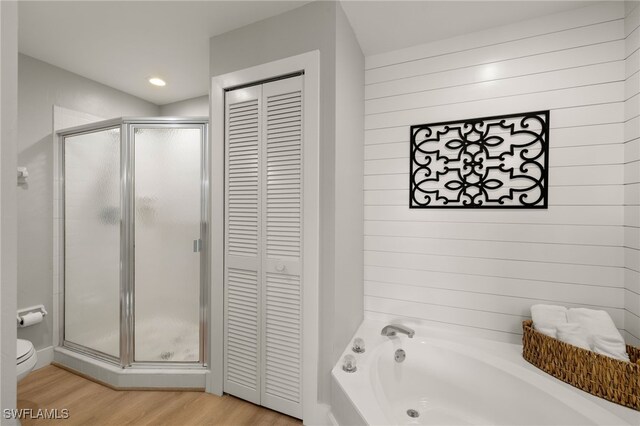 bathroom featuring a garden tub, a closet, toilet, a shower stall, and wood finished floors