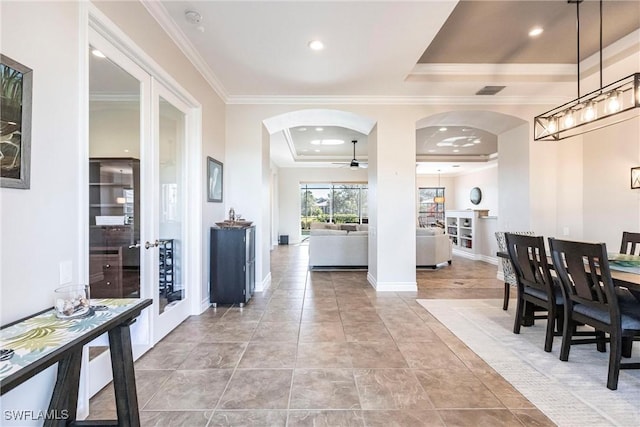 interior space with ceiling fan, a raised ceiling, crown molding, and french doors