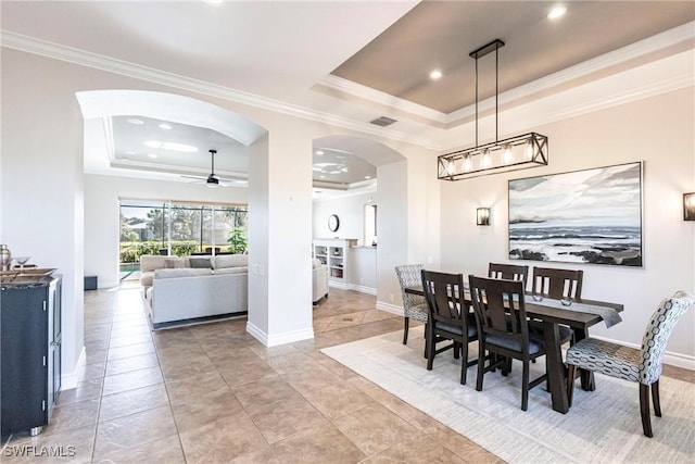 tiled dining room with a tray ceiling, ceiling fan, and ornamental molding