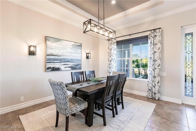 tiled dining space with ornamental molding and a tray ceiling