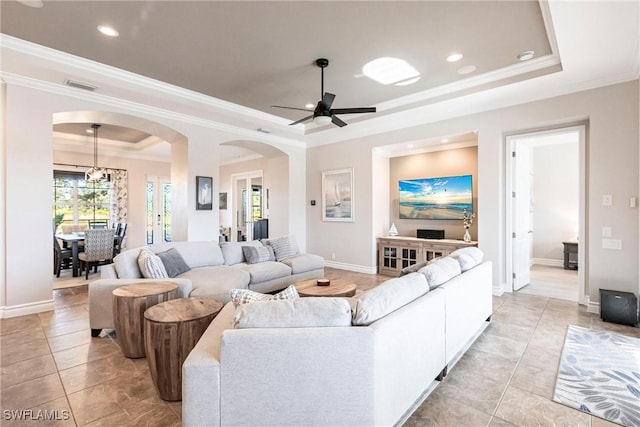 living room featuring ceiling fan, a raised ceiling, light tile patterned floors, and crown molding