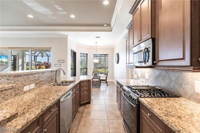 kitchen featuring light stone countertops, tasteful backsplash, stainless steel appliances, sink, and decorative light fixtures