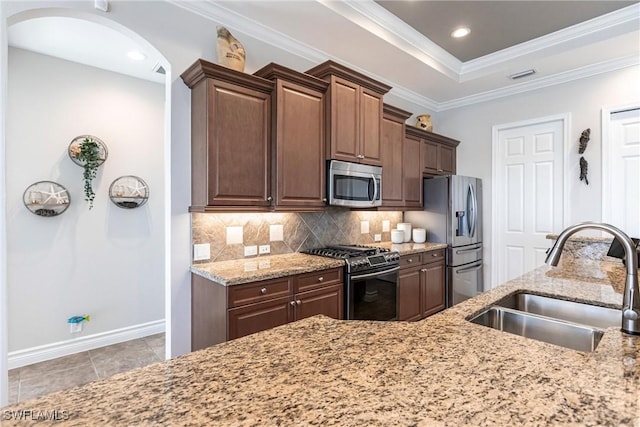 kitchen with sink, light stone countertops, ornamental molding, tasteful backsplash, and stainless steel appliances