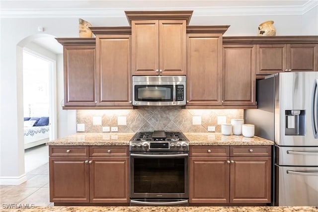 kitchen featuring appliances with stainless steel finishes, light tile patterned floors, tasteful backsplash, and light stone counters