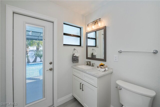 bathroom with baseboards, vanity, and toilet