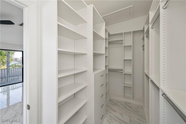 spacious closet featuring marble finish floor and attic access