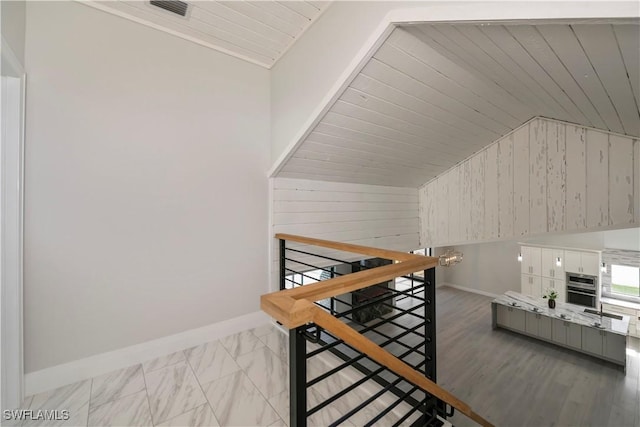 stairs with wooden walls, baseboards, wood ceiling, marble finish floor, and vaulted ceiling