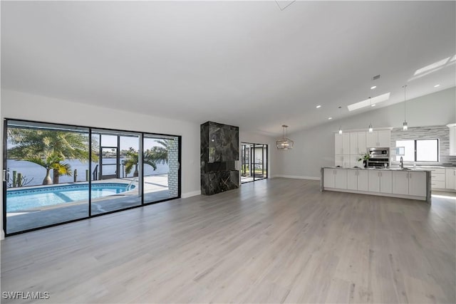 unfurnished living room with light wood-style floors, baseboards, a sink, and recessed lighting