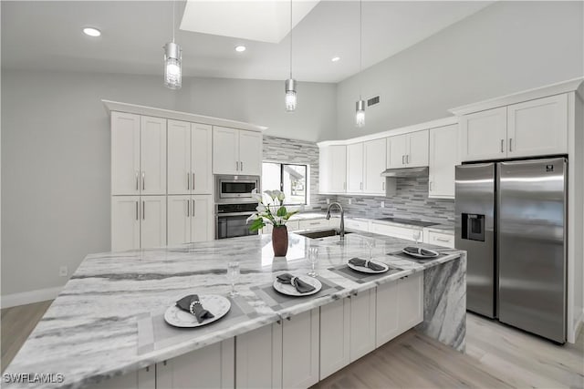 kitchen featuring appliances with stainless steel finishes, white cabinetry, a sink, and tasteful backsplash