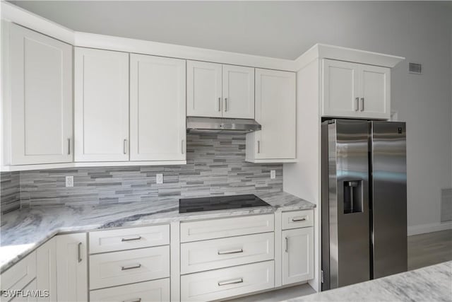 kitchen featuring stainless steel refrigerator with ice dispenser, visible vents, decorative backsplash, under cabinet range hood, and black electric cooktop